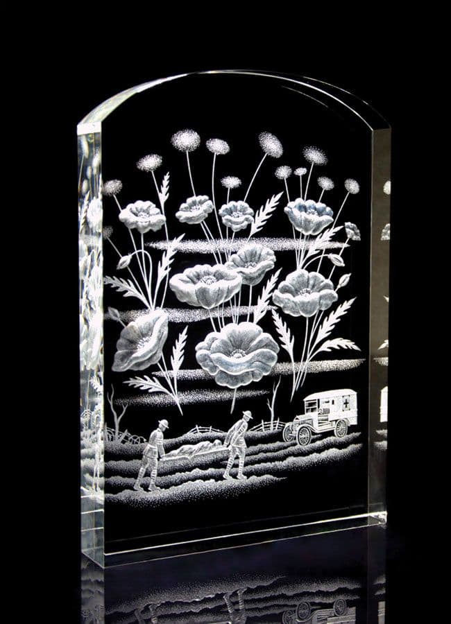 A crystal sculpture of a tombstone with flowers and two soldier carrying an injured comrade on a stretcher.