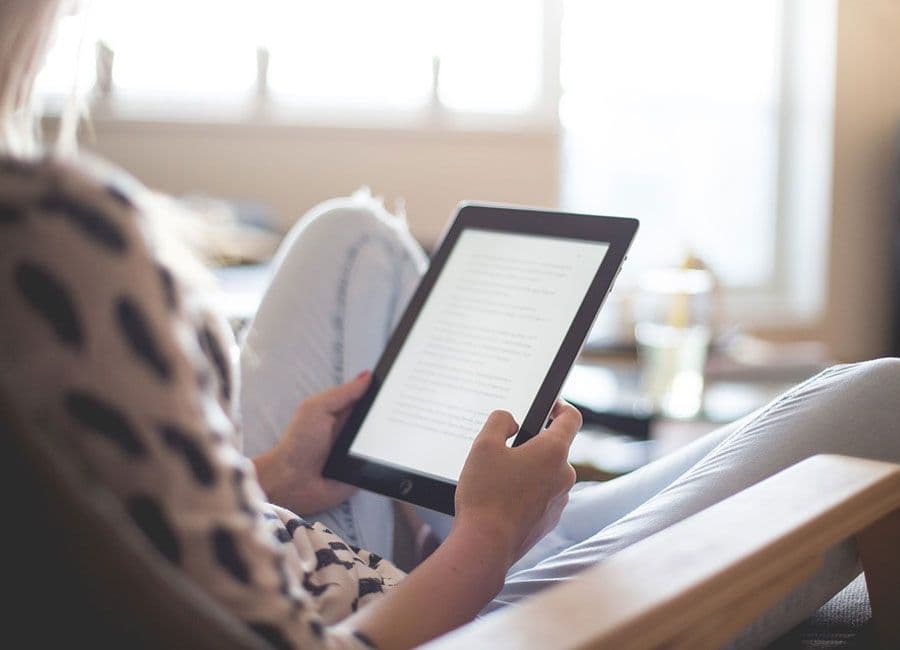 Someone reading from a tablet in a sunlit room.