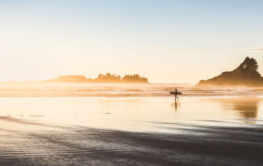 A photo of a surfer walking on the beach near sunset.