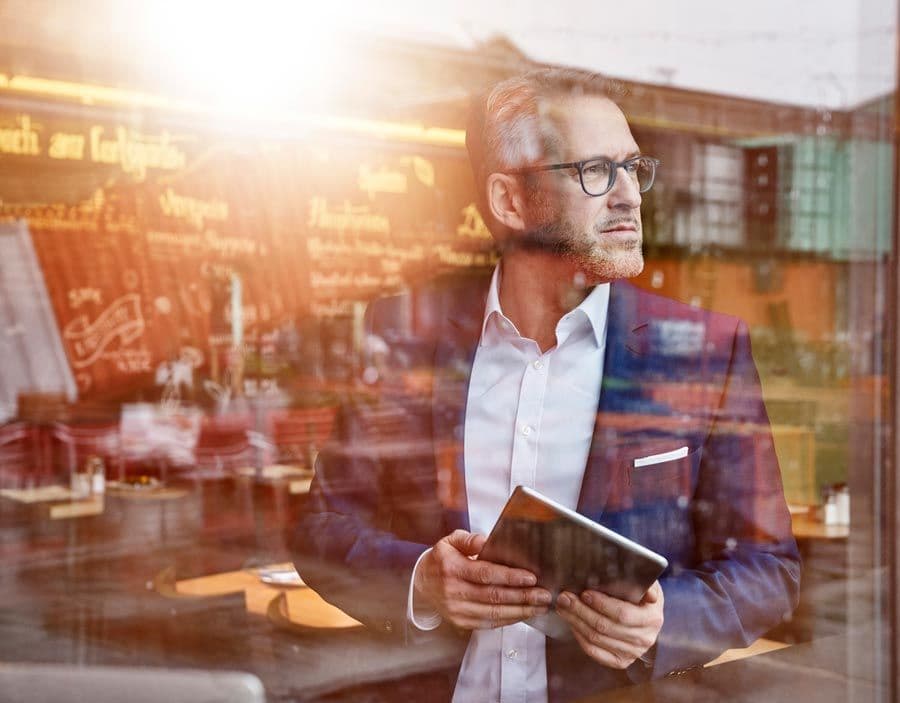 A man holding his tablet in a coffeeshop.