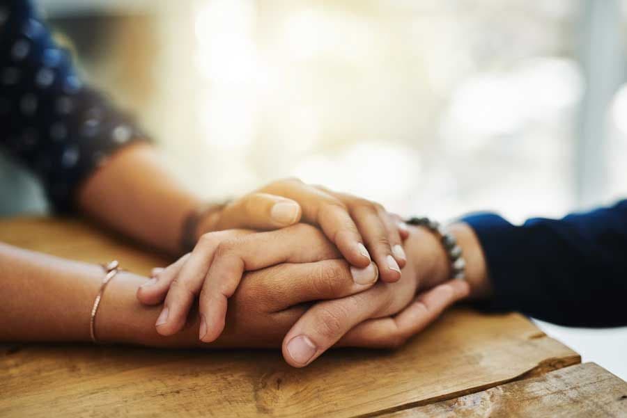 A man and a woman clasping hands on a table.